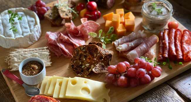 A picture from a charcuterie board party. The small charcuterie board contains a selection of meats, cheese and bread